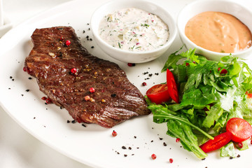Meat steak beef with fresh vegetables, herbs and two kinds of sauces on white dish