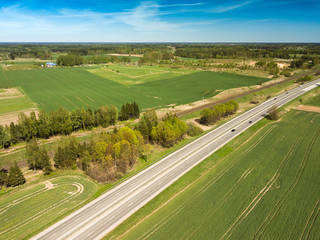 High-speed highway and railway, top view. Green field and blue sky.