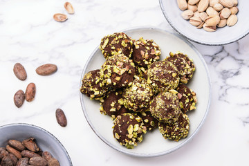 Homemade healthy vegan chocolate avocado truffles with pistachio in the bowl and ingredients on grey marble table. Organic energy vegetarian sweet balls