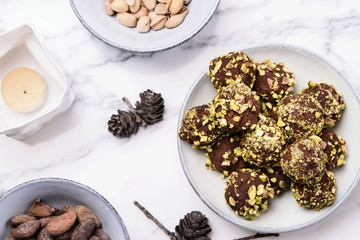 Homemade healthy vegan chocolate avocado truffles with pistachio in the bowl and ingredients on grey marble table     