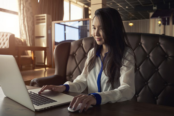 Cropped image of concentrated asian copywriter working remote in coffee shop and keyboarding new...