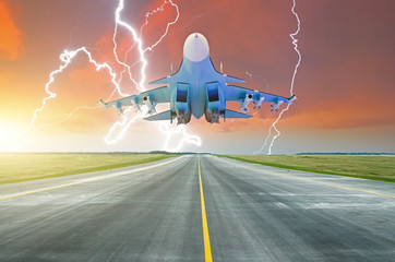 Fototapeta na wymiar Military fighter jet flies taxiway at the airport. Lightning strike on sunset thunderstorm.