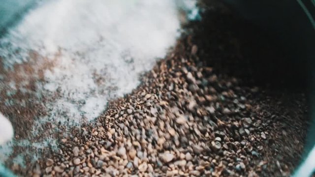 Closeup female hand sifts the chopped roasted coffee through a sieve - slow motion video