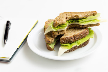 Sandwich from fresh toast with cheese and salad on work place. Work lunch