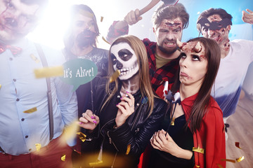 Friends in creepy costumes having fun at Halloween party