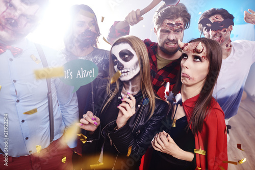 Friends in creepy costumes having fun at Halloween party