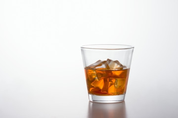 Glass of brandy and ice cubes on white background