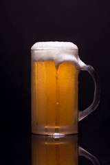 Cold beer with beer and reflection on dark background