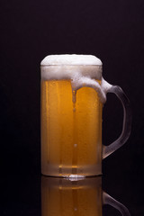 Cold cup with beer and foam, with reflection