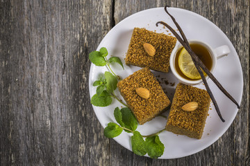Vegan pie Medovik decorated with almonds, vanilla and mint on a vintage wooden table flatlay