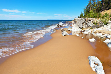 Beautiful sandy beach on the eastern shore of Lake Baikal with white stones and coastal forest on a...