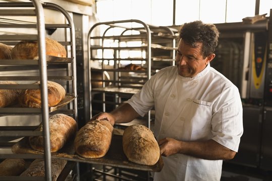 Male baker checking baked bread