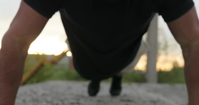 Young muscular guy doing push-ups, close up shot. Sport man, fitness muscle model guy making push ups exercise outdoor