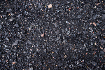 Black and gray asphalt with rocks background texture closup