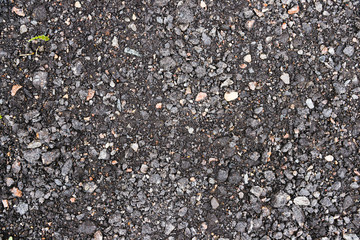 Black and gray asphalt with rocks background texture closup