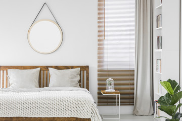 Window with wooden blinds and light grey curtain in white bedroom interior with mockup poster,...