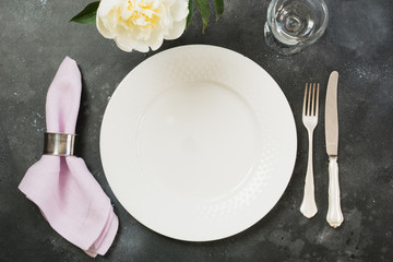 Romantic dinner. Table setting with white peony on black table. Top view.