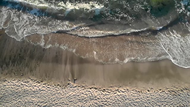 Aerial drone footage of crashing waves and sunset hitting the beach in Sinemorets Bulgaria.