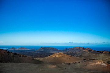 Fototapeta na wymiar If it wasn't the Ocean, this would look like Moon scape. The vast emptiness and loneliness of the Lanzarote black frozen lava volcanic desert with few sleeping volcanoes and almost clear blue sky