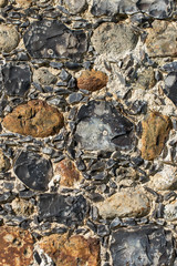 Old English stone town wall surface embedded with ancient flint.