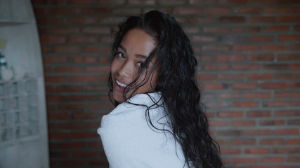 Naklejka premium Beautiful lady after shower covered in white towel relaxing on bed in her apartment. Portrait of fashion model girl indoors