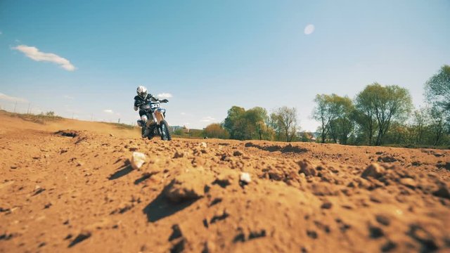 Slow motion footage of a motorcycler riding across dusty terrain. Slow motion