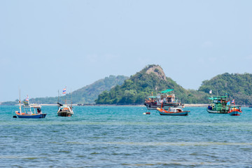 Wooden fishing boats anchor at the shallow water zone near a beach in Thailand on the sunny day.