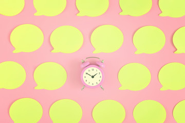 Bright, empty yellow stickers on a pink background. In the center is a small pink alarm clock.