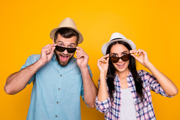 Portrait of surprised couple with unbelievable unexpected expression looking out black eyeglasses isolated on bright yellow background