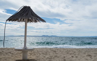 Sombrilla en una playa solitaria de la Costa Brava con mar revuelto y cielo nuboso en invierno