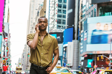 Young African American Man traveling in New York, wearing green short sleeve shirt, walking on busy...