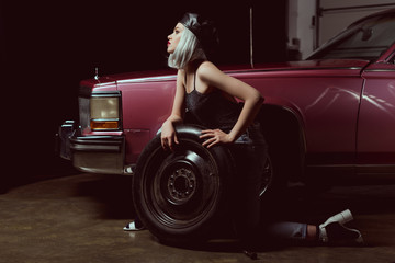 side view of sensual young woman repairing car wheel