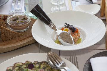 the Tartar from salmon with red caviar decorated with violet flowers and caramelized decoration