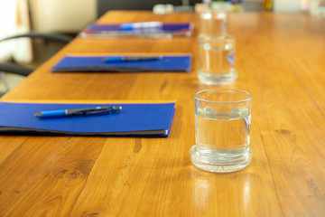 Empty conference room with glass water and notebook with pen on wooden table