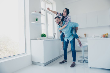 Full length portrait of funny comic couple, strong man carrying on back cheerful woman in piggy...