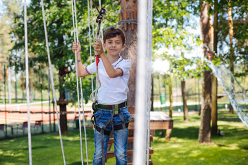 Enjoying himself. Joyful preteen boy having fun at a rope park and smiling pleasantly while moving...