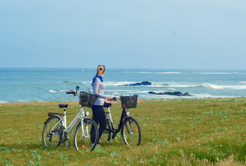 A girl with bicycles looks at the Ocean