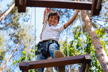 Not fear. Upbeat preteen boy being not afraid of height at rope park and looking down while walking...