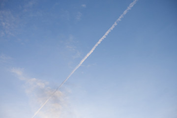 Fototapeta na wymiar Line of speed of the plane runs through the clouds on the sky. 