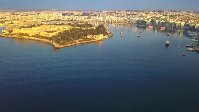 Valletta, Malta - 4K flying over Manoel Island with Sliema, Gzira and Ta'Xbiex at background with early in the morning warm sunlight
