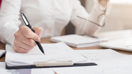 Young successful woman writing notes while sitting in office