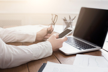 Woman manager working on laptop and holding phone