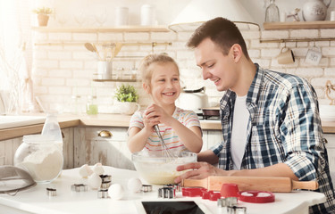 Father and daughter making cookies in kitchen