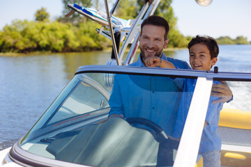 Precious bonding. Happy young man hugging his beloved little son while they sailing the motorboat...