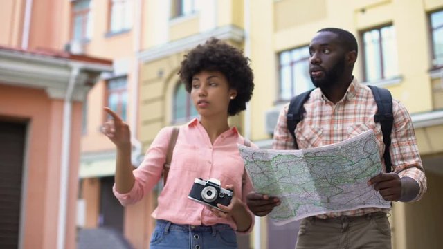 Young tourist couple with map and photo camera, choosing direction, travel