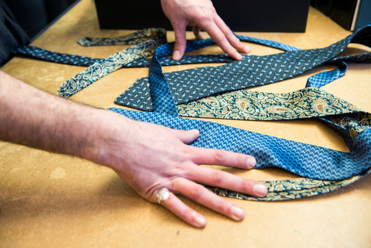 Customer choosing a tie on tailors shop table, detail of hands