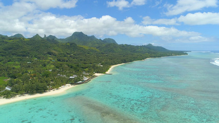 AERIAL: Spectacular view of beachfront hotel and mountains on exotic island.