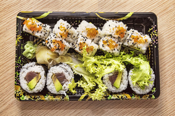 Japanese Cuisine: Tasty Uramaki and Futomaki served in the take-away box - selective focus