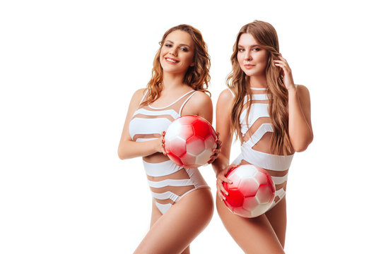 Pretty bikini models holding red balls in studio