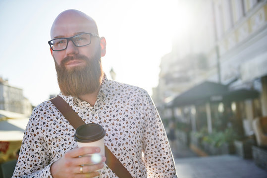Portrait of bearded man holding drink in disposable cup